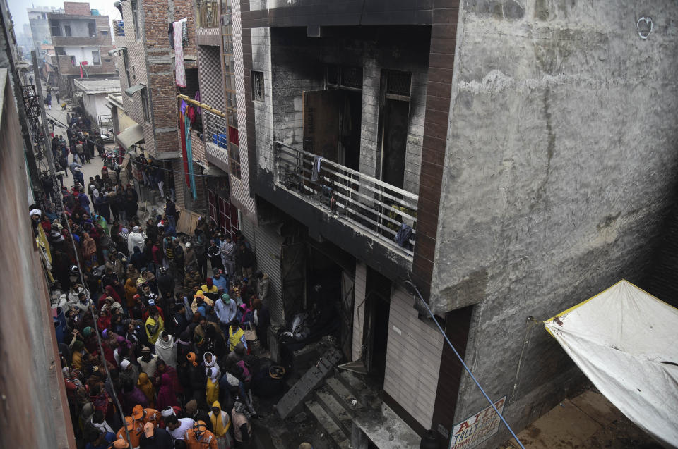 People gather around a warehouse where a fire broke out in the early hours of Monday at Kirari area of New Delhi, India, Monday, Dec.23, 2019. The blaze killed 9 people and left at least 3 injured, a fire official said. (AP Photo)