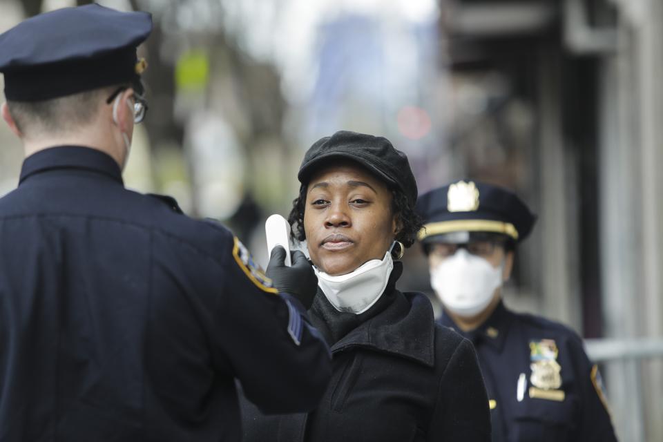 Officer Mahoney, left, screens people entering the 32nd precinct of the New York Police Department in an attempt to stem the spread of the new coronavirus Wednesday, April 15, 2020, in New York. (AP Photo/Frank Franklin II)