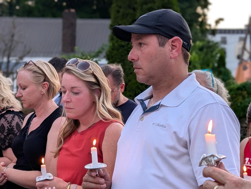 Adam Carney, brother of Matthew Carney, owner of Smokin Thighs in Nashville who died in a hit-and-run accident, holds a candle as community members remember the restaurant owner.