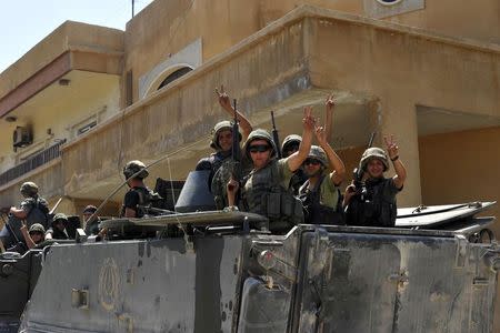 Lebanese army soldiers flash victory signs while riding on armoured carriers and military vehicles as they advance towards the Sunni Muslim border town of Arsal, in eastern Bekaa Valley as part of reinforcements August 6, 2014. REUTERS/Hassan Abdallah