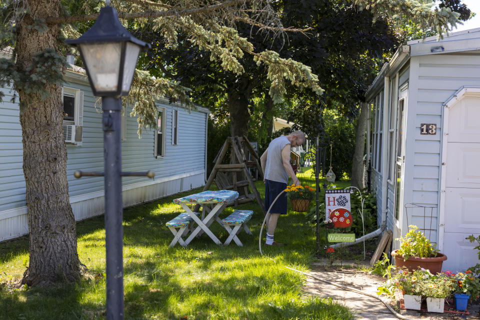 David Harm waters plants outside of his home in the Ridgeview Homes mobile home community in Lockport, N.Y., June 23, 2022. Harm is one of the mobile home residents participating in a rent strike in reaction to a proposed rent increase being introduced by new owners of the property. "They just want more money and they don't care what happens," said Harm. The plight of residents at Ridgeview is playing out nationwide as institutional investors, led by private equity firms and real estate trusts and sometimes funded by pension funds, swoop in to buy mobile home parks. (AP Photo/Lauren Petracca)