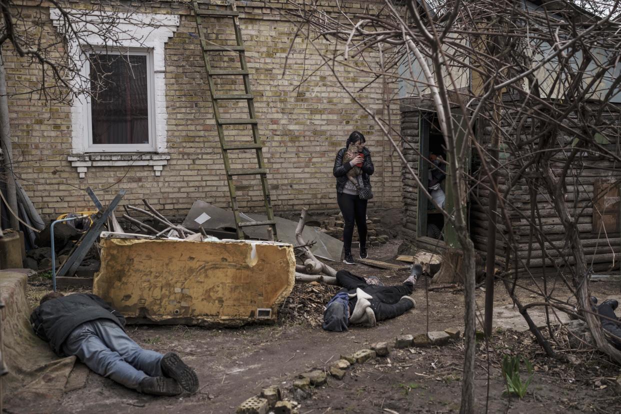 Ira Gavriluk holds her cat as she walks among the bodies of her husband, brother and another man who were killed outside her home in Bucha. (Felipe Dana / AP)