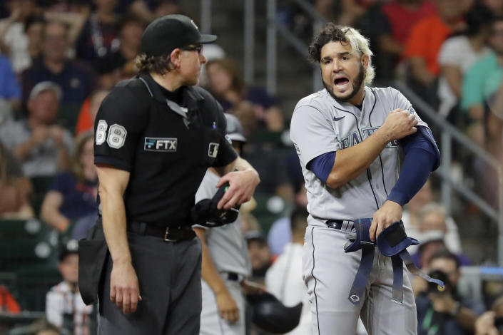 Seattle Mariners batter Eugenio Suarez, right, argues his strike out call with home plate umpire Chris Guccione, left, during the fifth inning of a baseball against the Houston Astros game Monday, June 6, 2022, in Houston. (AP Photo/Michael Wyke)