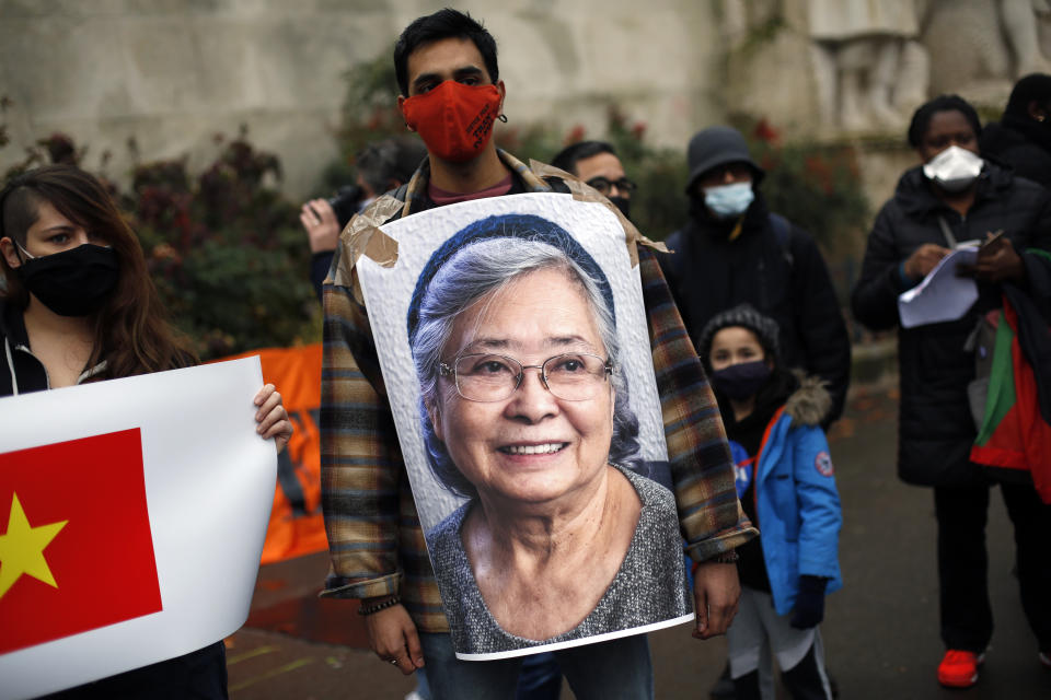 An activist holds a picture of Tran To Nga, a 78-year-old former journalist, during a gathering in support of people exposed to Agent Orange during the Vietnam War, in Paris, Saturday Jan. 30, 2021. Activists gathered Saturday in Paris in support of people exposed to Agent Orange during the Vietnam War, after a French court examined a case opposing a French-Vietnamese woman to 14 companies that produced and sold the toxic chemical. (AP Photo/Thibault Camus)