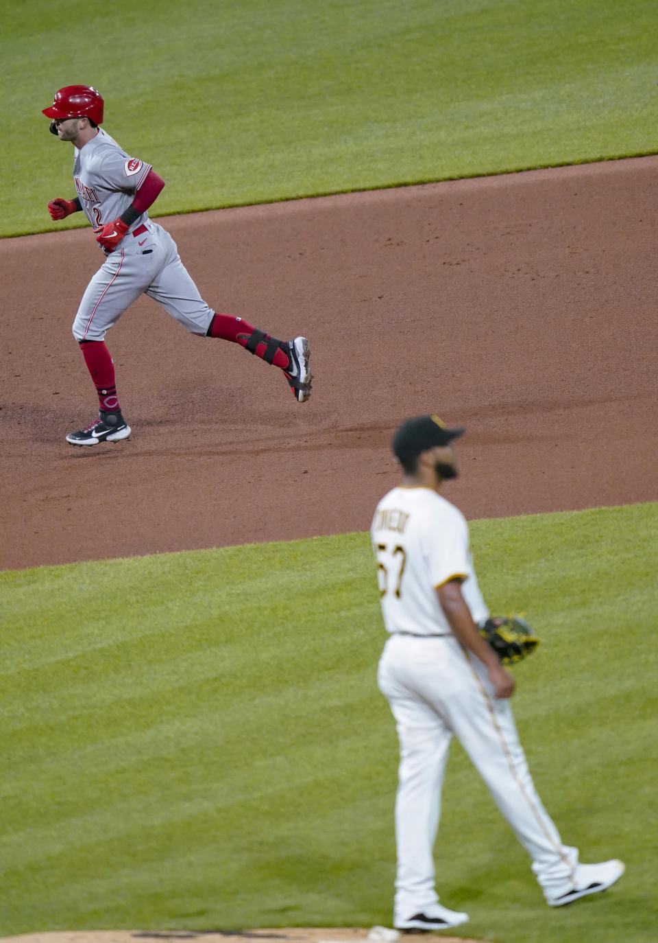 Cincinnati Reds' Tyler Naquin, left, rounds the bases after hitting a three-run home run off Pittsburgh Pirates starting pitcher Luis Oviedo, right, in the seventh inning of a baseball game, Monday, May 10, 2021, in Pittsburgh. (AP Photo/Keith Srakocic)