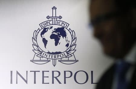 FILE PHOTO: A man passes an Interpol logo during the handing over ceremony of the premises for Interpol's Global Complex for Innovation, a research and development facility, in Singapore September 30, 2014. REUTERS/Edgar Su