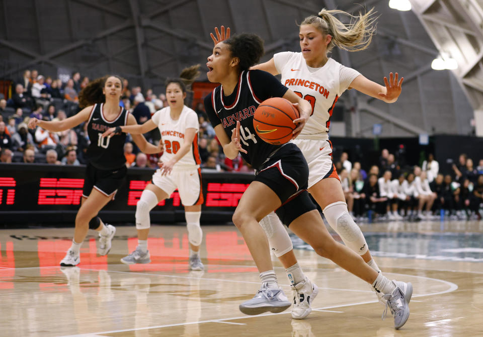 Harvard guard Harmoni Turner (14) drives to the basket against Princeton forward Ellie Mitchell (00) during the first half of the Ivy League championship NCAA college basketball game, Saturday, March 11, 2023, in Princeton, N.J. (AP Photo/Noah K. Murray)