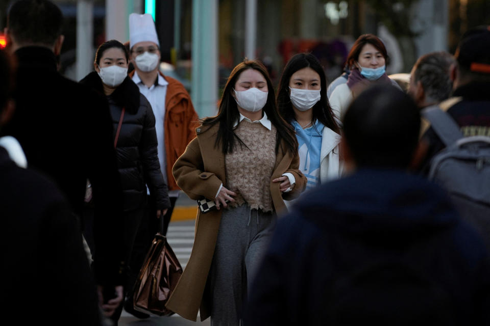 People wearing masks cross a street in Shanghai, China. The FTSE was treading water after stock markets in Asia slumped