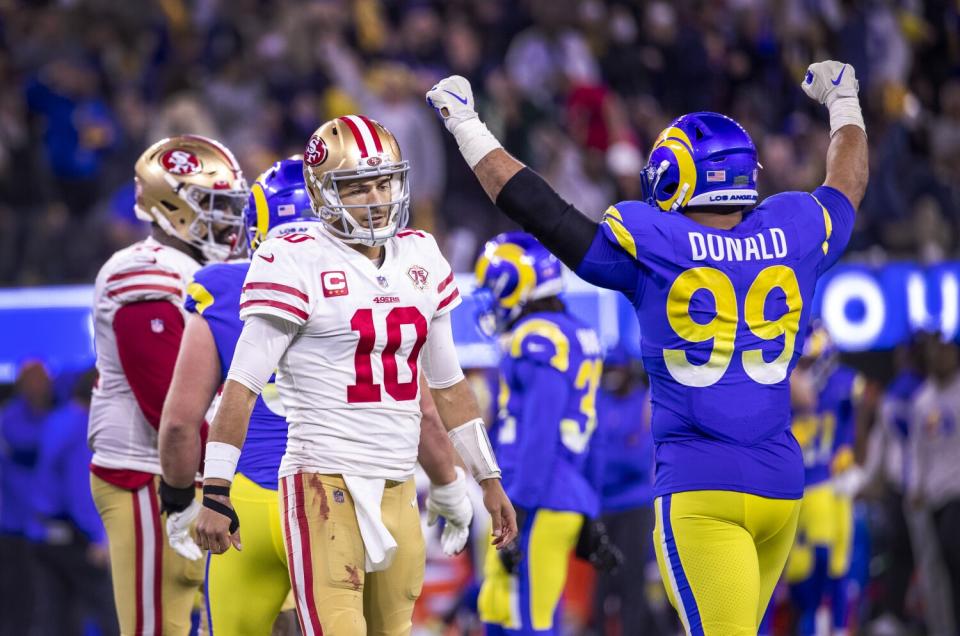 Rams defensive lineman Aaron Donald (99) celebrates as 49ers quarterback Jimmy Garappolo walks away dejectedly.