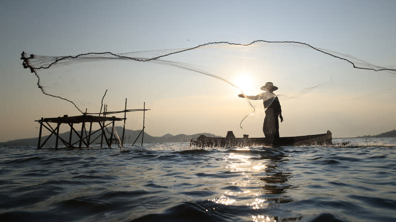 asian man tossing fishing net