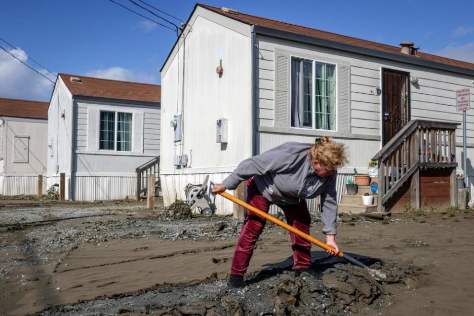 Bertha Ruval shovels thick layers of mud from her driveway at a mobile home park in Pajaro, California, on 23 March.