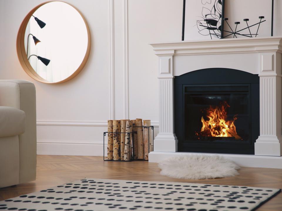 round mirror and white faux fireplace in room