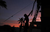 <p>Kainalu Kitashima hands his father a piece of wood to help tie down their tiny home in preparation for Hurricane Lane, Wednesday, Aug. 22, 2018, along Ewa Beach in Honolulu. As emergency shelters opened, rain began to pour and cellphone alerts went out, the approaching hurricane started to feel real for Hawaii residents. (Photo: John Locher/AP) </p>