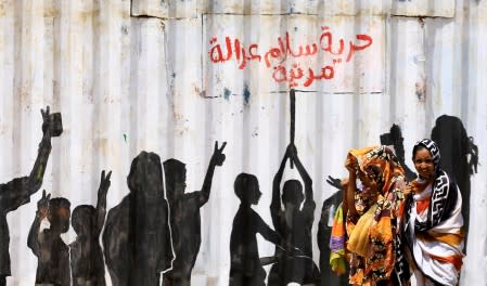 FILE PHOTO: Civilians walk past graffiti reading in Arabic "Freedom, Peace, Justice and Civilian" in the Burri district of Khartoum