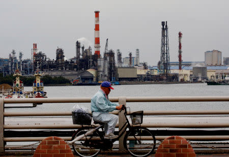 FILE PHOTO: A man cycles past chimneys of facotries at the Keihin Industrial Zone in Kawasaki, Japan September 12, 2018. REUTERS/Kim Kyung-Hoon