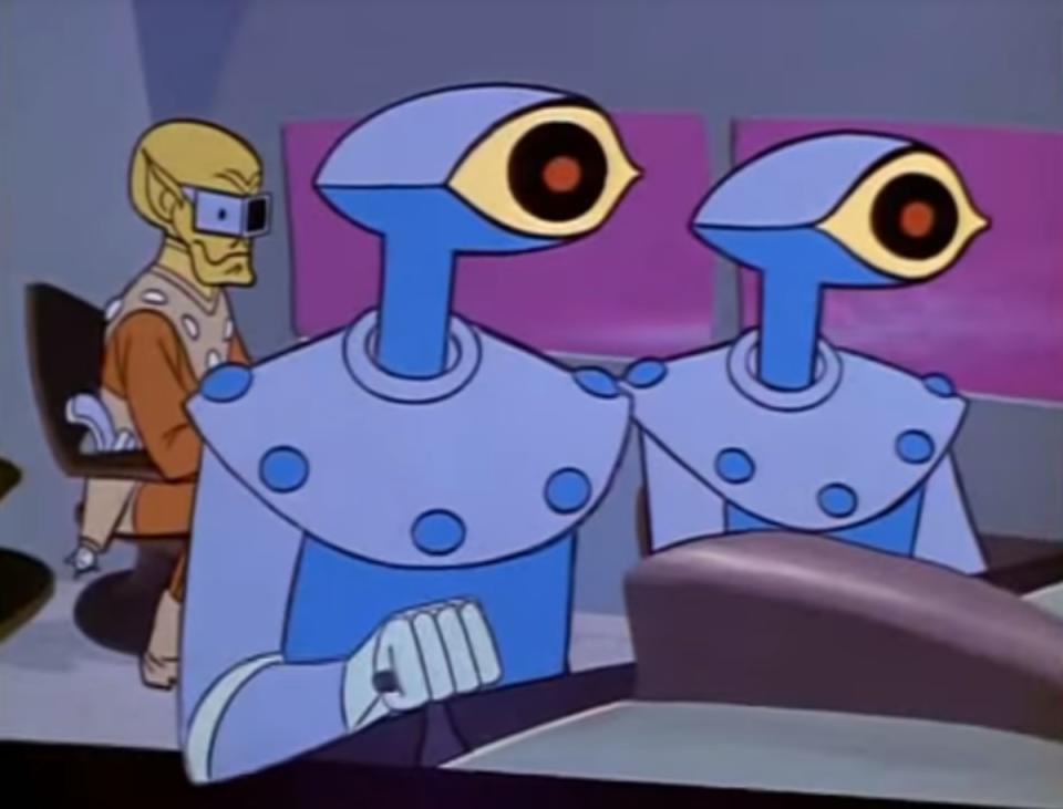 Two one-eyed robots fly a ship with a green, bald-headed alien in the background.