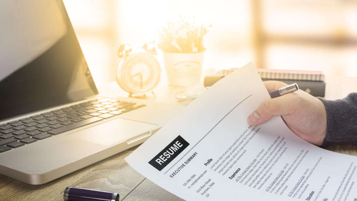  Man holding resume in front of a computer 