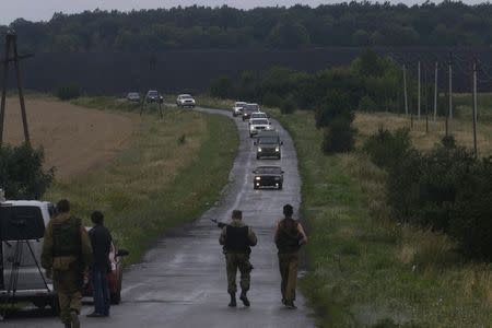 Pro-Russian separatists watch as Organisation for Security and Cooperation in Europe (OSCE) monitors arrive at the crash site of Malaysia Airlines flight MH17, near the settlement of Grabovo in the Donetsk region, July 18, 2014. REUTERS/Maxim Zmeyev