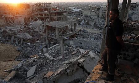 A Palestinian man looks out of his heavily damaged house at neighbouring houses which witnesses said were destroyed during the Israeli offensive, in the east of Gaza City September 3, 2014. REUTERS/Suhaib Salem/Files