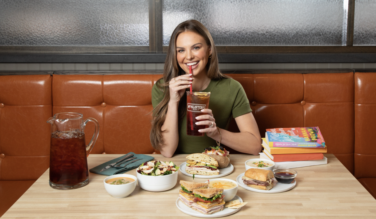 hannah brown sitting at a booth with plates of food and books at the table