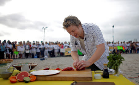 FILE PHOTO: The Naked Chef Jamie Oliver slices fish during an appearance on NBC's "Today" show in Miami Beach, Florida February 22, 2008. REUTERS/Eric Thayer/File Photo