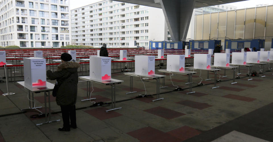 People wait in front of heating stations to warm the COVID-19 test in a set up for rapid new coronavirus testing in Vienna, Austria, Monday, Nov. 30, 2020. The Austrian government has moved to restrict freedom of movement for people, in an effort to slow the onset of the COVID-19 disease and the spread of the coronavirus. (AP Photo/Ronald Zak)