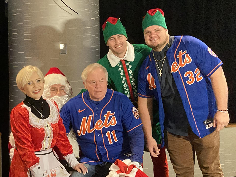 CORRECTS THAT METS TODD ZEILE IS DRESSED AS SANTA, NOT FRANCISCO LINDOR AS ORIGINALLY SENT - From left to right: Angela Showalter, wife of New York Mets manager Buck Showalter; Mets Todd Zeile as Santa Claus; Buck Showalter; center fielder Brandon Nimmo as elf; and designated hitter Daniel Vogelbach at the Mets holiday party at Citi Field in New York on Thursday, Dec. 15, 2022. (AP Photo/Ron Blum)