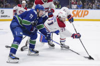 Vancouver Canucks' Nils Hoglander (21) and Montreal Canadiens' Jake Evans (71) vie for the puck during the third period of an NHL hockey game in Vancouver, British Columbia, Thursday, March 21, 2024. (Darryl Dyck/The Canadian Press via AP)