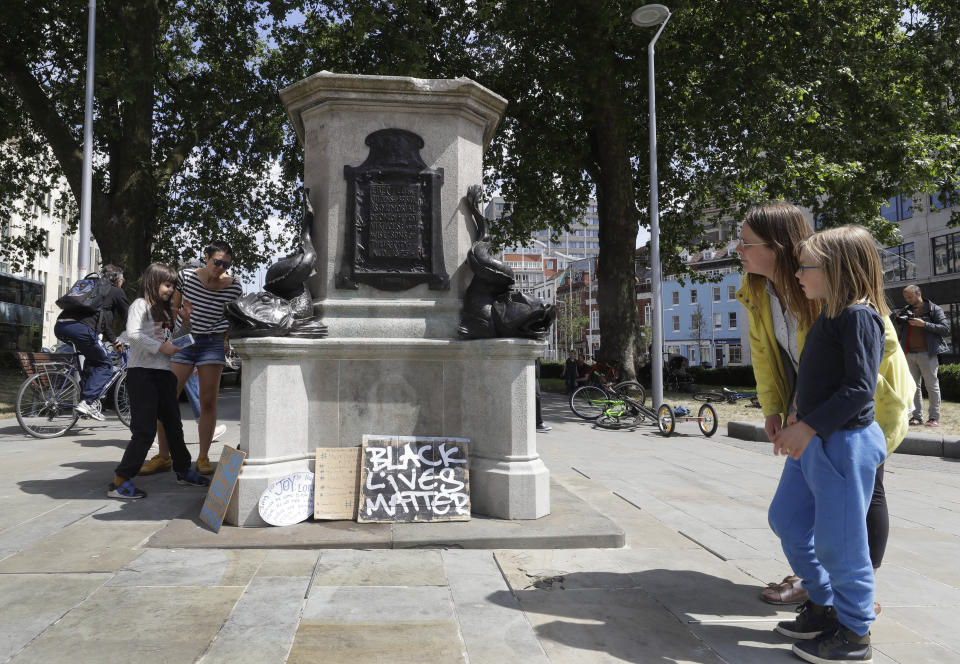 People look at the pedestal of the toppled statue of Edward Colston in Bristol, England, Monday, June 8, 2020, following the downing of the statue on Sunday at a Black Lives Matter demo. The toppling of the statue was greeted with joyous scenes, recognition of the fact that he was a notorious slave trader — a badge of shame in what is one of Britain’s most liberal cities. (AP Photo/Kirsty Wigglesworth)