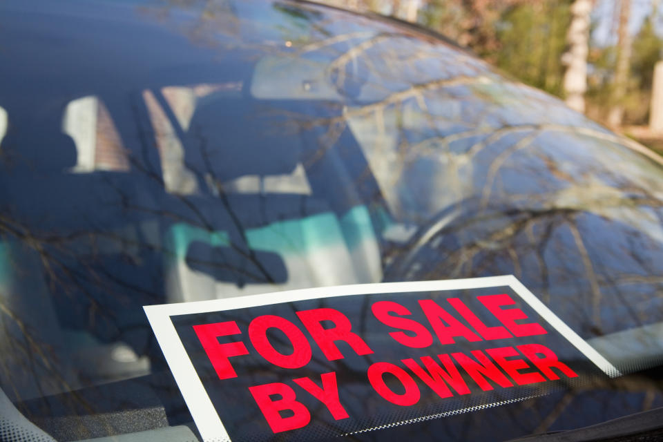 Sign on car windshield reads "FOR SALE BY OWNER"