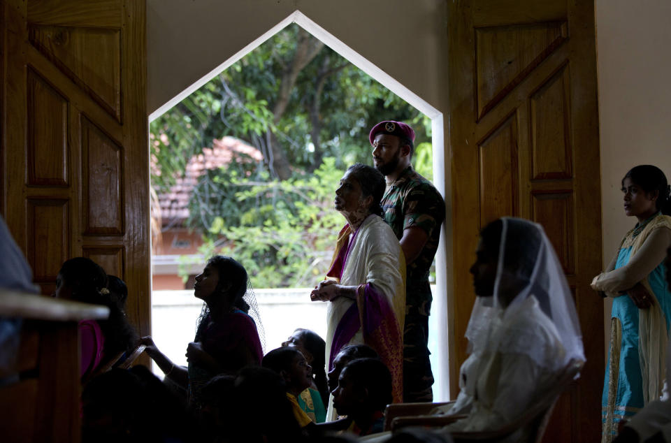 A soldier stands guard amid Catholics attending Mass at St. Joseph's church, Tuesday, April 30, 2019, in Thannamunai, Sri Lanka. This small village in eastern Sri Lanka has held likely the first Mass since Catholic leaders closed all their churches for fear of more attacks after the Easter suicide bombings that killed over 250 people.