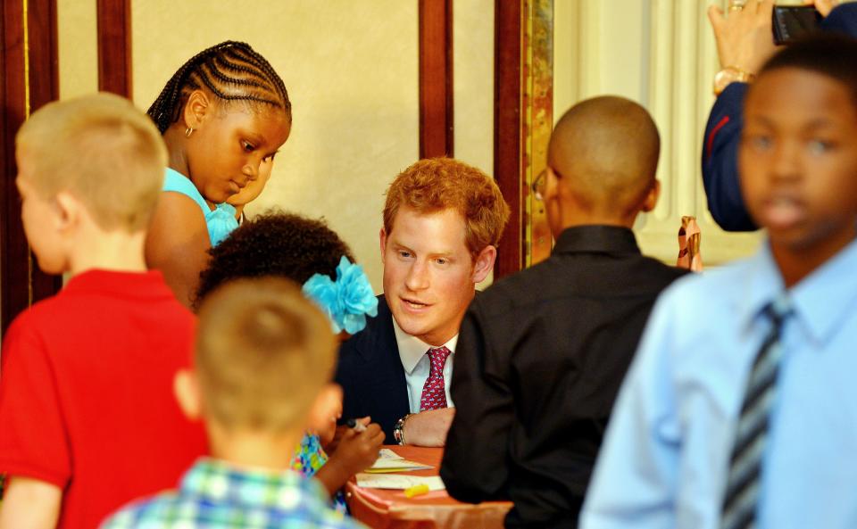 Prince Harry laughs with children who are making giftbags of edible dough jewellery, bouquets of roses and baked crisps for their mothers (PA)