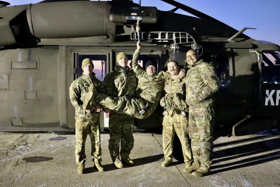 Staff Sgt. Matthew Medeiros, a Rhode Island Army National Guard paramedic, celebrates his team's high-altitude rescue of two avalanche survivors from an Albanian mountainside on Jan. 22 with a playful pose on the hoist of a Black Hawk helicopter. From left, Capt. Mark Dente, a pilot; Staff Sgt. Ryan Farley, a paramedic; Medeiros; Chief Warrant Officer Joshua Mason, a pilot instructor; and the copter's crew chief, Sgt. Brandon Bessette.