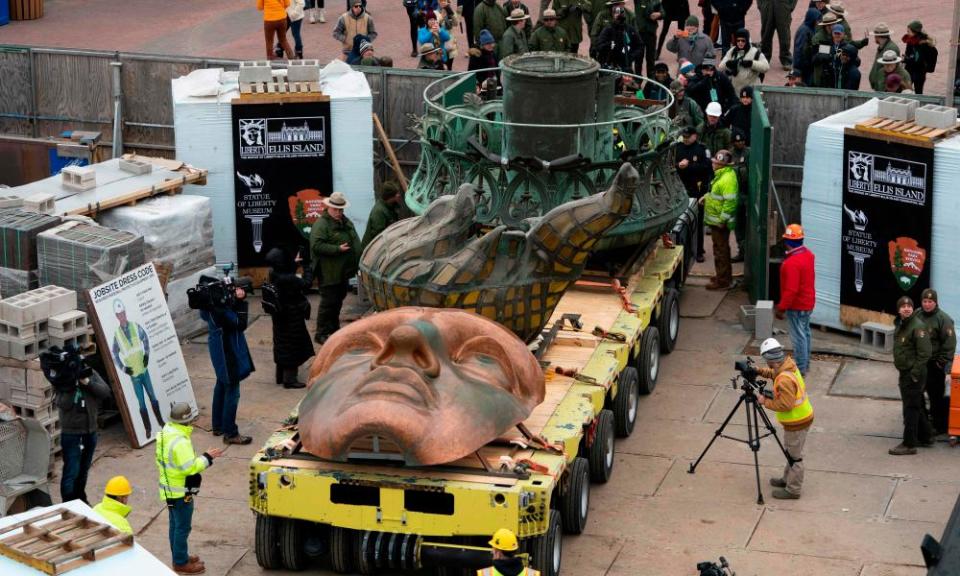 Workers transport the Statue of Liberty’s original torch along with a replica of the statue’s face to its permanent home in the new Statue of Liberty Museum.