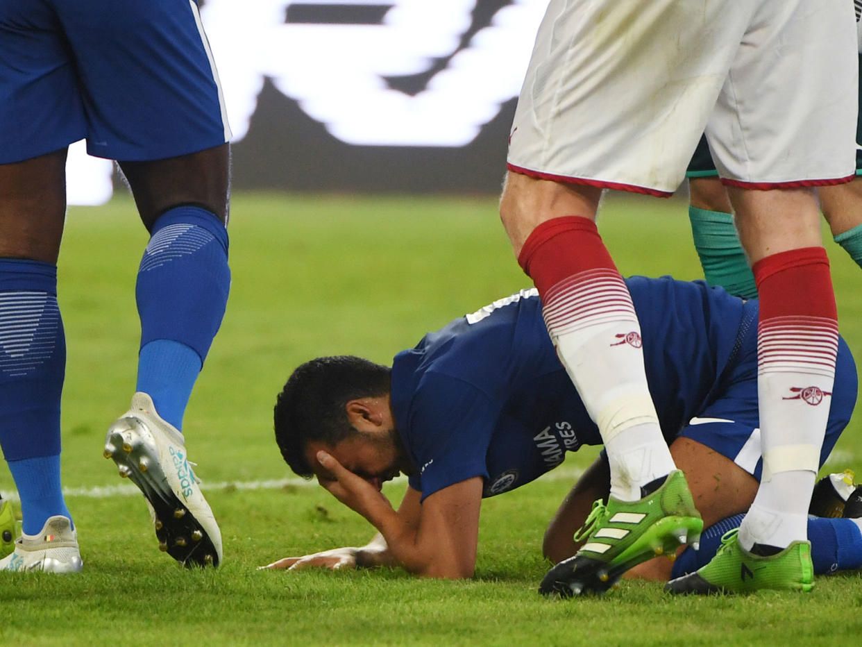 Pedro holds his head after colliding with Arsenal 'keeper David Ospina: Getty