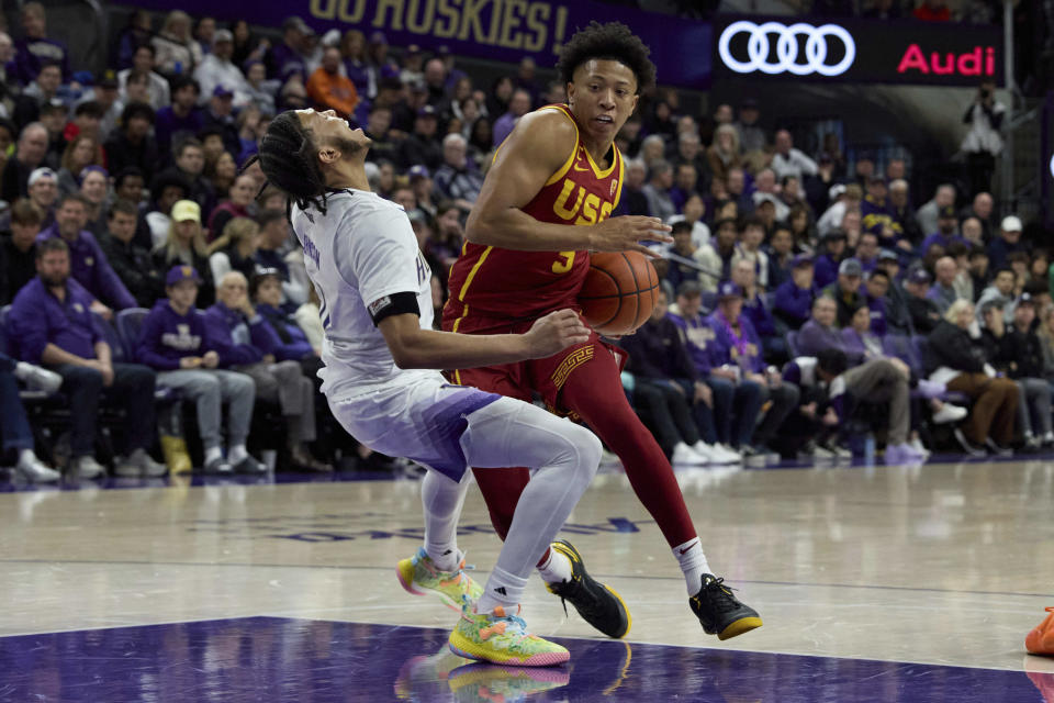 Southern California guard Boogie Ellis, right, draws a foul from Washington guard Koren Johnson, left, during the second half an NCAA college basketball game, Saturday, March 2, 2024, in Seattle. (AP Photo/John Froschauer)