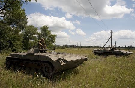 Members of the self-proclaimed Donetsk People's Republic forces sit on armored vehicles after withdrawing them further from the frontline in a field on the suburbs of Debaltseve in Donetsk region, Ukraine, July 21, 2015. REUTERS/Kazbek Basaev