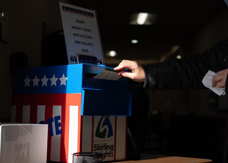 A woman places her absentee ballot in a drop box at the Sterling Heights Senior Center in Sterling Heights on Monday, November 2, 2020 during in-person absentee voting.