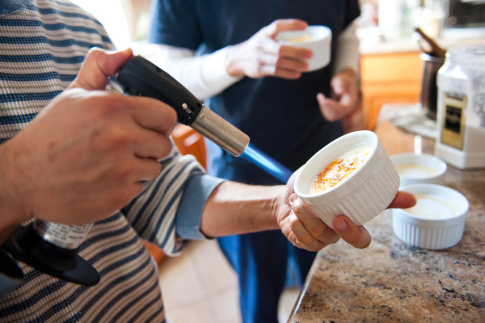 someone using a cooking torch on crème brûlée