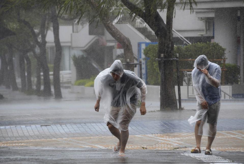 People struggle against strong wind and rain caused by approaching Typhoon Vongfong as they wallk on a street in Naha on Japan's southern island of Okinawa, October 11, 2014. (REUTERS/Kyodo)