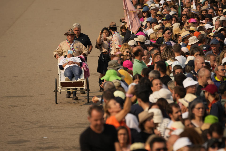 A worshipper is helped out of the crowd after Pope Francis arrived at Our Lady of Fatima shrine in Fatima, central Portugal Saturday, Aug. 5, 2023. Pope Francis is in Portugal through the weekend into Sunday's 37th World Youth Day to preside over the jamboree that St. John Paul II launched in the 1980s to encourage young Catholics in their faith. (AP Photo/Francisco Seco)