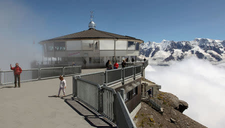 Tourists are seen in front of the world's first revolving restaurant, known as Piz Gloria from the 1969 James Bond movie "On Her Majesty's Secret Service", which was filmed there, on the peak of the Schilthorn mountain (altitude 2970 m/ 9744 feet) at the Bernese Oberland, Switzerland August 7, 2012. REUTERS/Arnd Wiegmann