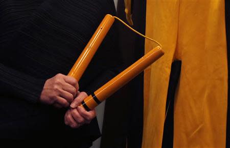 Anna Lee, vice chairman of Chinese auction house Spink, poses with nunchaku and a jumpsuit, both used by the late kungfu superstar Bruce Lee in his last movie "Game of Death", as part of the Bruce Lee 40th anniversary collection, at a news conference in Hong Kong December 2, 2013. REUTERS/Bobby Yip