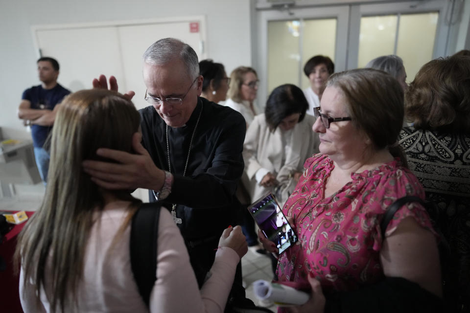 Rev. Silvio Baez, center left, auxiliary bishop of Managua, Nicaragua, attends to parishioners following Mass at St. Agatha Catholic Church, which has become the spiritual home of the growing Nicaraguan diaspora, Sunday, Nov. 5, 2023, in Miami. For Baez, one of his concelebrant priests and many in the pews who have had to flee or were exiled from Nicaragua recently, the Sunday afternoon Mass at the Miami parish is not only a way to find solace in community, but also to keep pushing back against the Ortega regime's violent suppression of all critics, including many Catholic leaders. (AP Photo/Rebecca Blackwell)