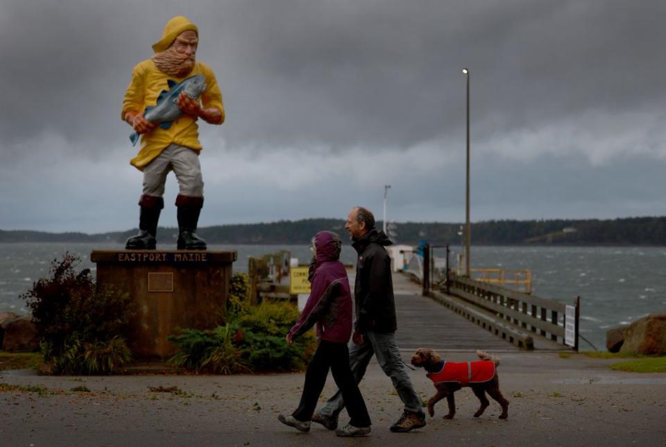 People walk as the wind and rain from Post-Tropical Cyclone Lee affects the area on Saturday in Eastport, Maine.