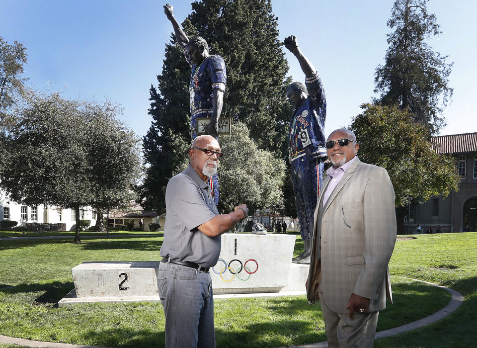 FILE - In this Oct. 17, 2018, file photo, John Carlos, left, and Tommie Smith pose for a photo in front of statue that honors their iconic, black-gloved protest at the 1968 Olympic Games, on the campus of San Jose State University in San Jose, Calif. Tommie Smith and John Carlos are part of the 2019 U.S. Olympic and Paralympic Hall of Fame class that will be inducted later this year. (AP Photo/Tony Avelar, File)