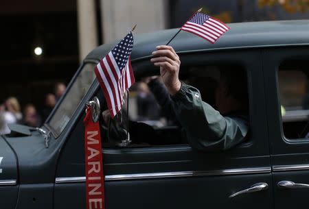 A United States Marine veteran waves the U.S. flag as he drives a World War Two era vehicle during the Veterans Day parade on 5th Avenue in New York November 11, 2014. REUTERS/Mike Segar