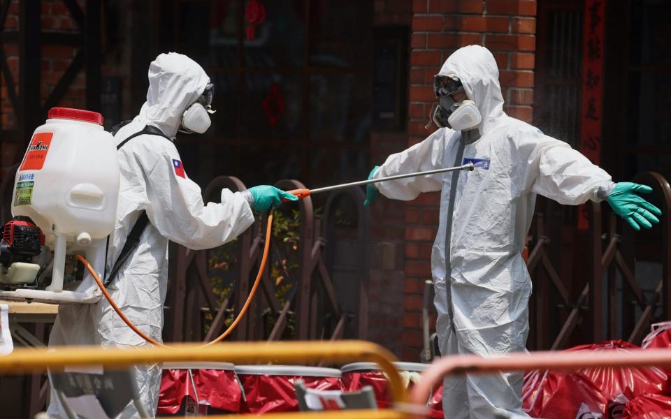 A soldier disinfects his colleague at a testing center in Taipei, Taiwan -  ANN WANG / REUTERS