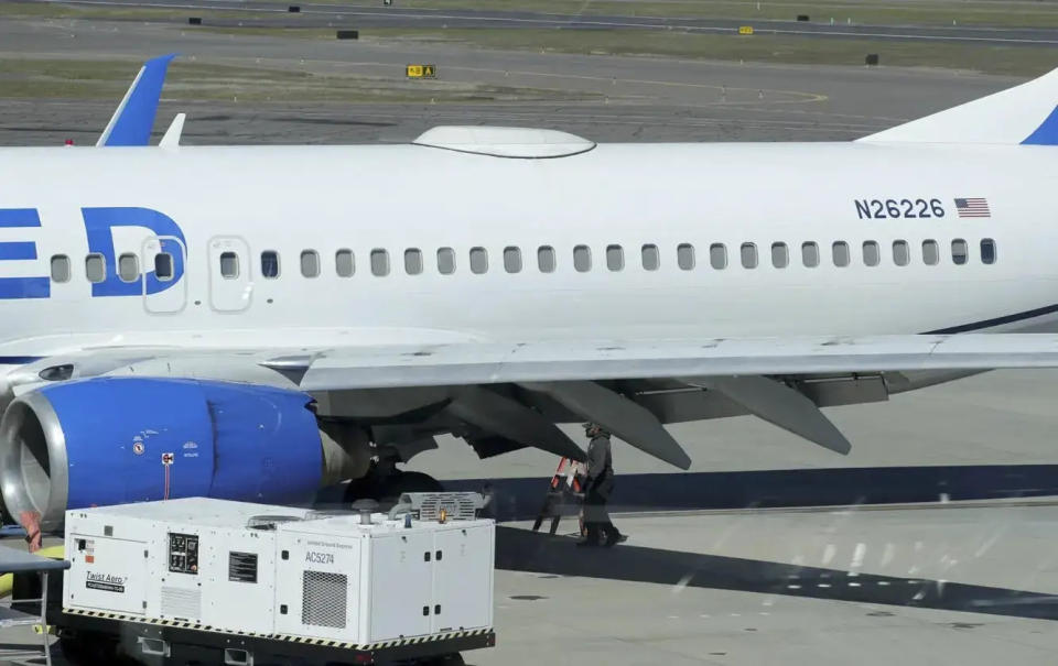 A Medford Jet Center worker walks under a United Boeing 737-824 that landed at Rogue Valley International-Medford Airport from San Francisco with a missing panel Friday, March 15, 2024, in Medford, Ore. (Andy Atkinson/Rogue Valley Times via AP)