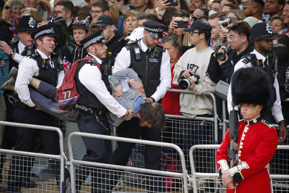 Policías retiran a un hombre que corrió en la ruta de la procesión real en el paseo The Mall en Londres antes del Desfile del Estandarte el jueves 2 de junio de 2022, en el primero de cuatro días de celebraciones por el Jubileo de Platino de la reina Isabel II por sus 70 años de servicio. (AP Photo/David Cliff)